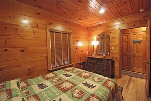 Ein Zimmer mit Holzwänden, einem Bett, einem Schminktisch, einem Spiegel und einer Tür mit der Aufschrift 'Wäscherei'.