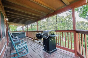 Eine überdachte Terrasse im Freien mit Grill, Whirlpool und Schaukelstuhl.