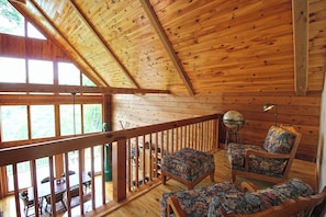 Ein Holzhütten-Innenraum mit Balkon, Holzboden und Essbereich.