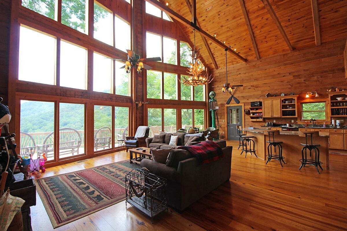 Amplia sala de estar con un gran ventanal, chimenea y una zona de cocina con taburetes de bar.