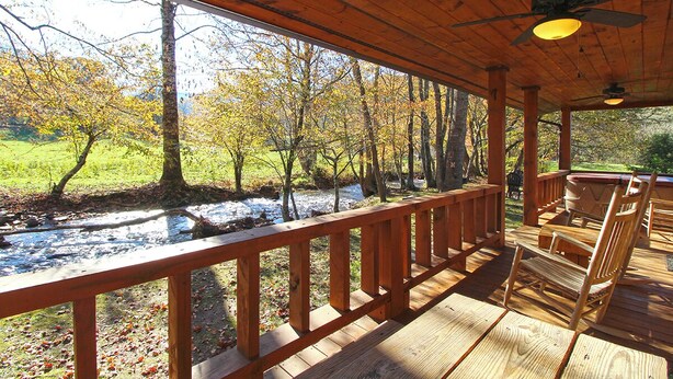 A wooden deck with a railing overlooking a river and trees. - Trout Creek Cabin- Right on the Creek (Whittier)