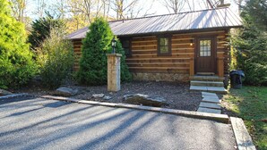 A log cabin with a stone foundation, a wooden door, and a small porch. - Trout Creek Cabin- Right on the Creek (Whittier)