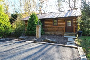 Eine Blockhütte mit Steinunterbau, einer Holztür und einer kleinen Veranda.