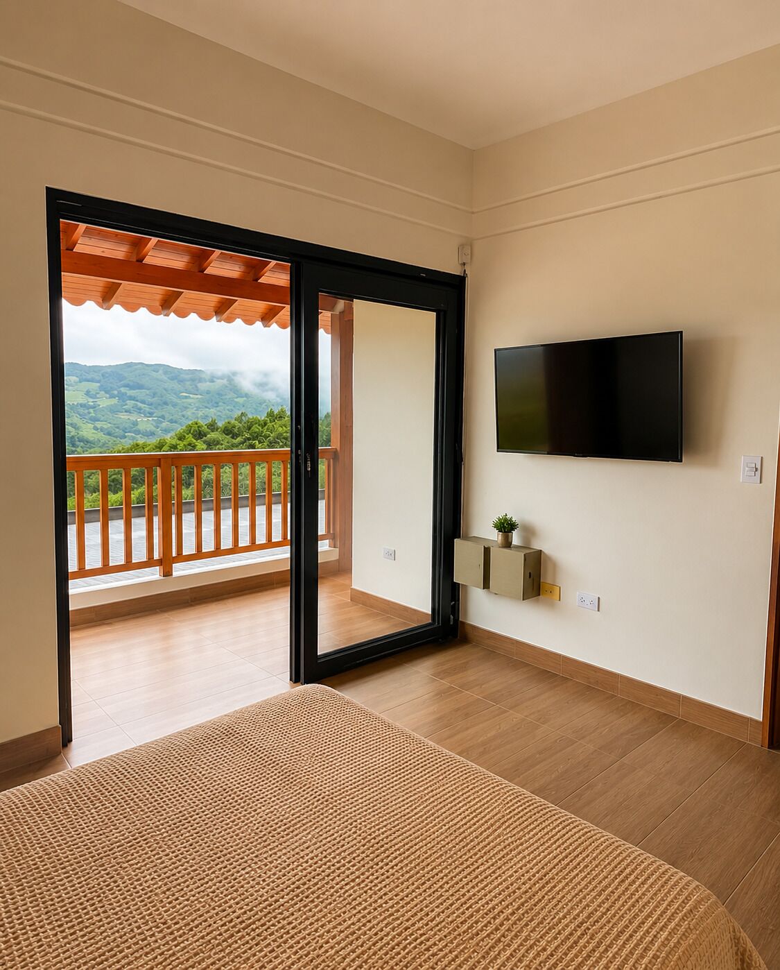 A room with a large sliding glass door leading to a balcony with a view of green hills.
