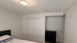 A bedroom with a bed, a wardrobe, a desk, and a door. - A bright, clean walking-out basement unit in Surrey,near White-rock. (Surrey)