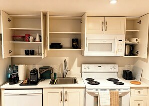 Une petite cuisine équipée d’un four à micro-ondes, d’une cuisinière, d’un évier et d’un égouttoir à vaisselle.