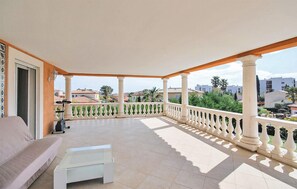 Ein Balkon mit einer Couch, einem kleinen Tisch und Blick auf umliegende Gebäude und Grünflächen.