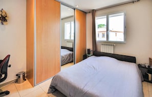 Een slaapkamer met een bed, een spiegel, een raam en een radiator.