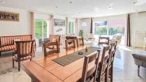 A spacious living area with a large wooden dining table, multiple chairs, a sofa, and a television mounted on the wall. - Gorgeous home in FREJUS with private swimming pool, can be inside or outside (FREJUS)
