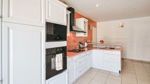 A modern kitchen with white cabinetry, a black oven, and a marble countertop. - Gorgeous home in FREJUS with private swimming pool, can be inside or outside (FREJUS)