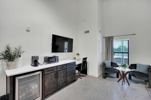 A compact living space with a kitchenette, a flat-screen TV mounted on the wall, a dining area with a round table, and a sofa set. - The Lawson District (Midlothian)