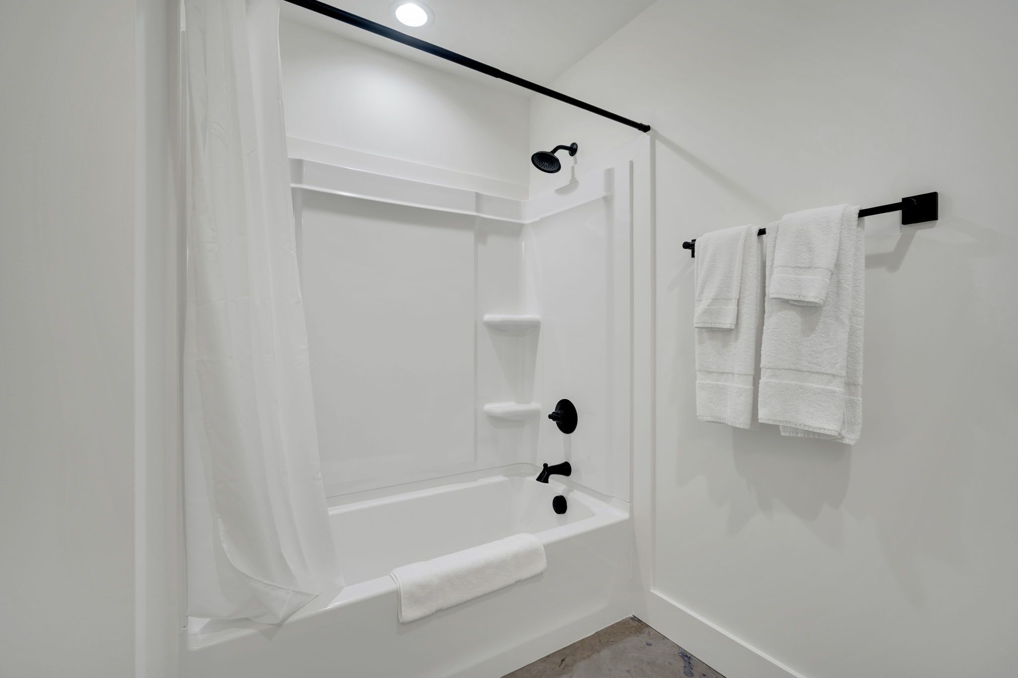 A white bathroom with a bathtub, shower, and towel rack.