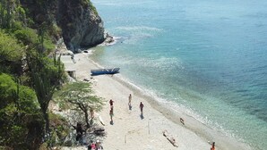 A beach with clear water, a boat, and people walking. - Eco House | Private and Quiet Loft | Perfect for Long Stays (Taganga)