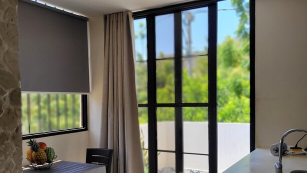 A modern kitchen with a built-in sink, a dining area with a table and chairs, and a large window with curtains. - Eco House | Private and Quiet Loft | Perfect for Long Stays (Taganga)
