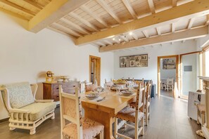 A dining area with a wooden table set for four, surrounded by wooden chairs. A sofa and a small cabinet are visible in the background. - Family Home Margherita Pool Mugello 2, Vicchio, Italy (Vicchio)