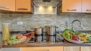 Eine Küche mit Herd, Töpfen, Spüle und frischem Gemüse.
