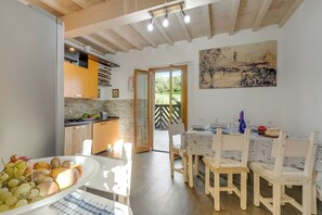 A kitchen with wooden cabinets, a dining area with a table and chairs, and a painting on the wall. - Family Home Margherita Pool Mugello 4, Vicchio, Italy (Vicchio)