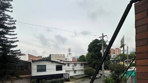 Eine Wohnstraße mit Häusern, blauem Himmel und Blick auf ein entferntes Gebäude mit einem Turm.