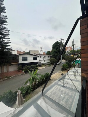 A residential street with houses, a clear sky, and a view of a distant building with a tower. - Luxury Duplex Loft AC Rooftop Jacuzzi Laureles (Medellín)