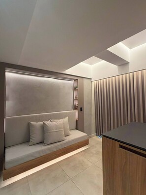 A modern room with a built-in sofa, a wooden desk, and a large window with curtains. - Luxury Duplex Loft AC Rooftop Jacuzzi Laureles (Medellín)