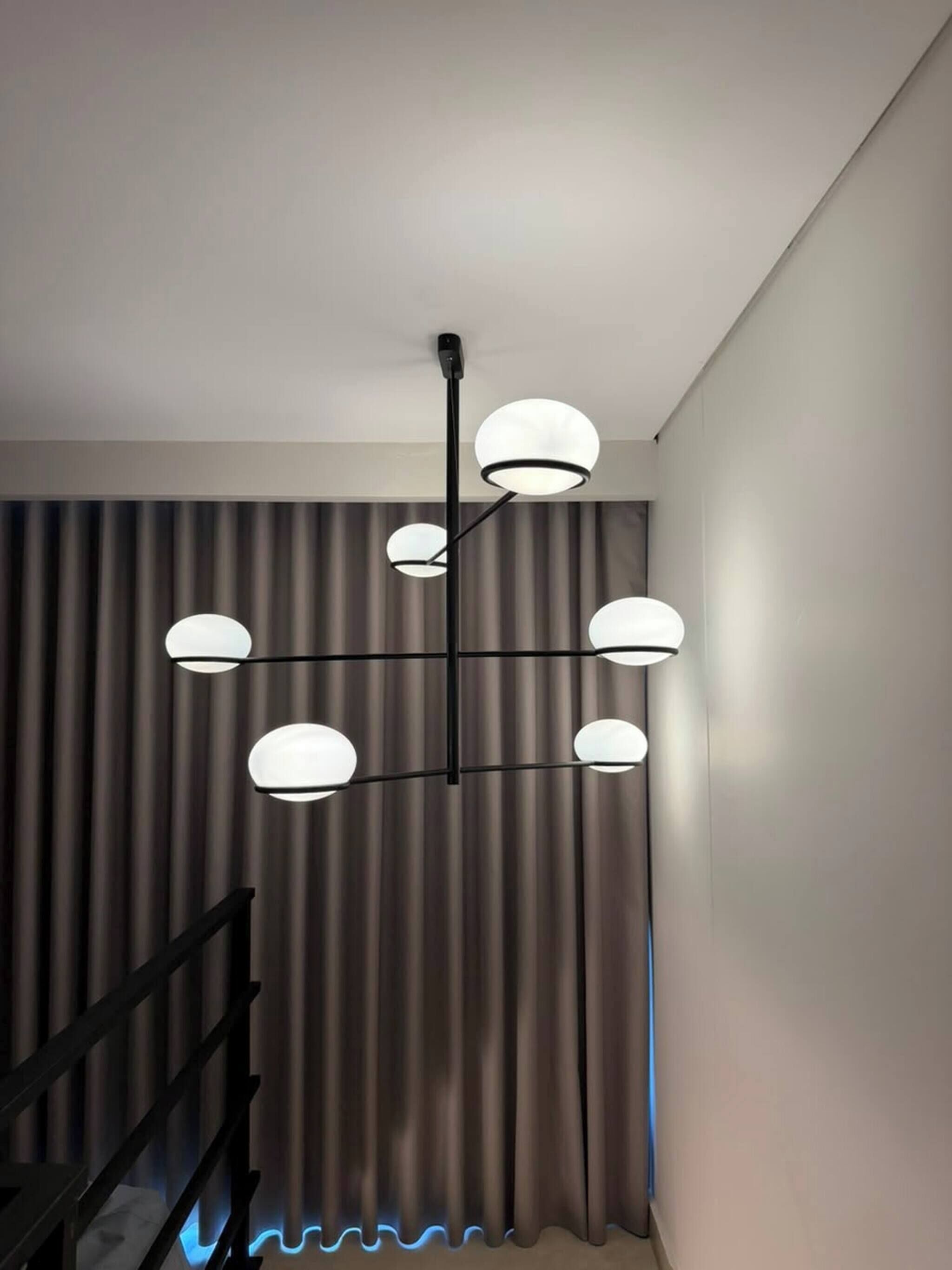 Un intérieur moderne avec un luminaire fixé au plafond et un escalier.