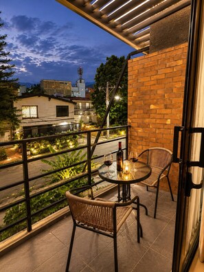 A balcony with a table and chairs, a bottle of wine, and a candle. - Luxury Duplex Loft AC Rooftop Jacuzzi Laureles (Medellín)
