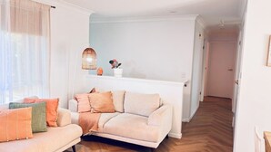 Ett vardagsrum med en soffa, en golvlampa och en krukväxt.