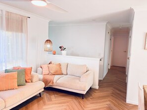 Ein Wohnzimmer mit einer Couch, einer Stehlampe und einer Topfpflanze.