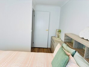 Ein Schlafzimmer mit Bett, Kommode, Spiegel und Tür.