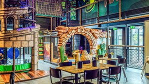 Ein Restaurant mit einem rustikalen Bogen, Holztischen, schwarzen Stühlen und einer Kamelstatue.