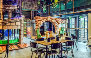 Ein Restaurant mit einem rustikalen Bogen, Holztischen, schwarzen Stühlen und einer Kamelstatue.