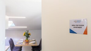 Een eethoek met een tafel voor vier personen, een vaas met bloemen en een bordje met de tekst 'NEDA TOP FLOOR APARTMENT'.