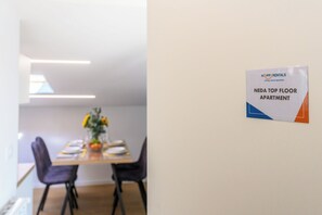 A dining area with a table set for four, a vase with flowers, and a sign indicating 'NEDA TOP FLOOR APARTMENT.' - Neda Apt Top Floor: Terrace Views in Goriška Brda, Dobrovo v Brdih, Slovenia (Dobrovo v Brdih)