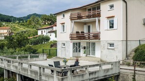 Een gebouw met twee verdiepingen, voorzien van een balkon, een patio met tuinmeubilair en uitzicht op het omliggende landschap.