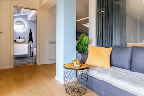 A modern living room with a sofa, round coffee table, and a view into the kitchen. - Neda Apt Top Floor: Terrace Views in Goriška Brda, Dobrovo v Brdih, Slovenia (Dobrovo v Brdih)