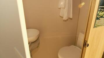 Un baño pequeño con inodoro, lavabo y ducha.