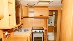 A compact kitchenette with a sink, stove, oven, and a toilet.