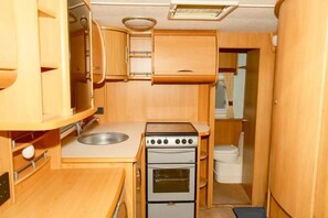 A compact kitchenette with a sink, stove, oven, and a toilet. - Sundale Caravan Retreat 2 Berth - Wanaka (Wānaka)