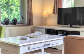A room with a TV, a lamp, a table with a tray, and two potted plants by a window. - 3 bedroom stunning home in Den Ham (Den Ham)