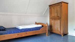 A single bed with a wooden headboard, a wardrobe, and a white ceiling. - 3 bedroom stunning home in Den Ham (Den Ham)