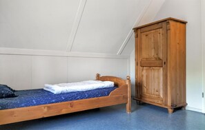 A single bed with a wooden headboard, a wardrobe, and a white ceiling. - 3 bedroom stunning home in Den Ham (Den Ham)