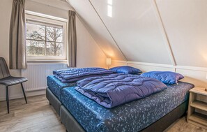Een slaapkamer met een bed, een stoel, een raam en een lamp.