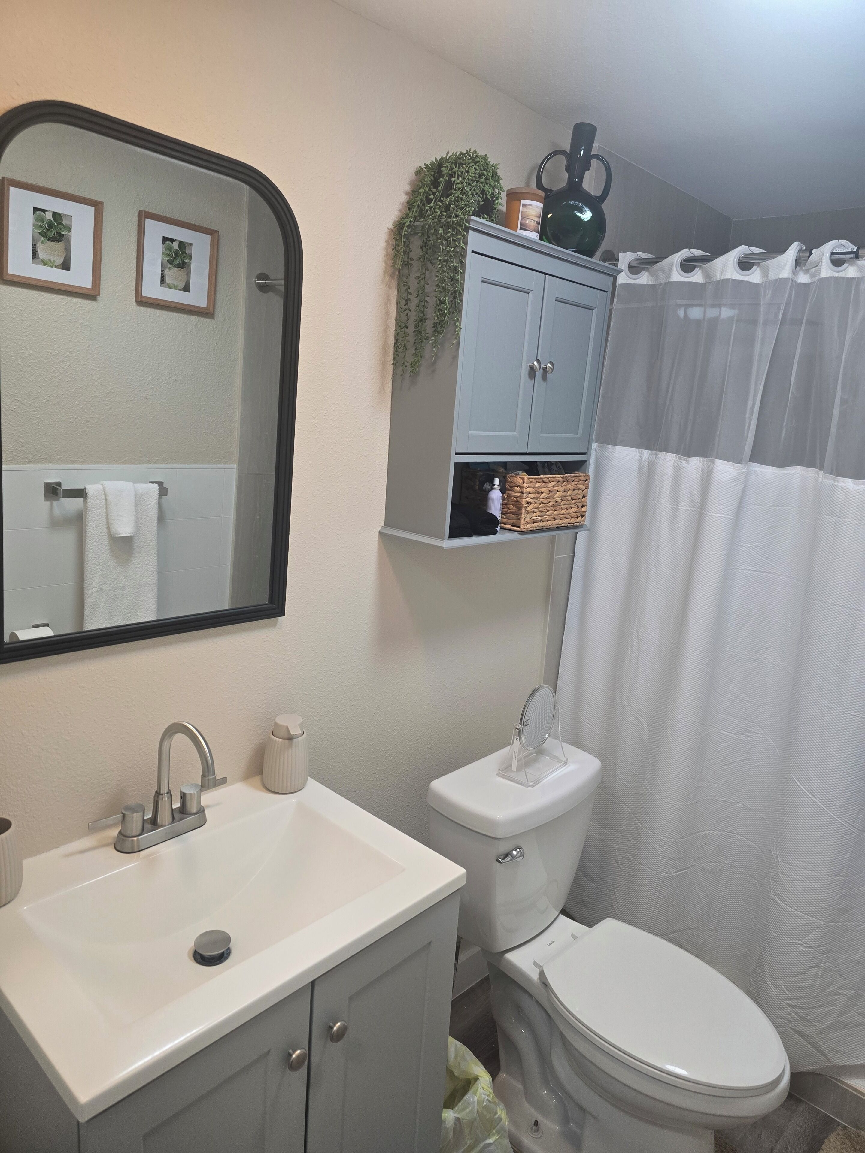 A bathroom with a white sink, a toilet, a mirror, and a shower curtain.