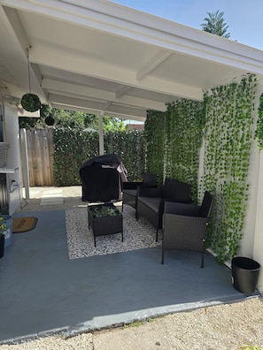 A covered patio with a grill, outdoor furniture, and a decorative wall with climbing plants. - Cozy 1-bedroom studio in charming Sarasota. (Sarasota)