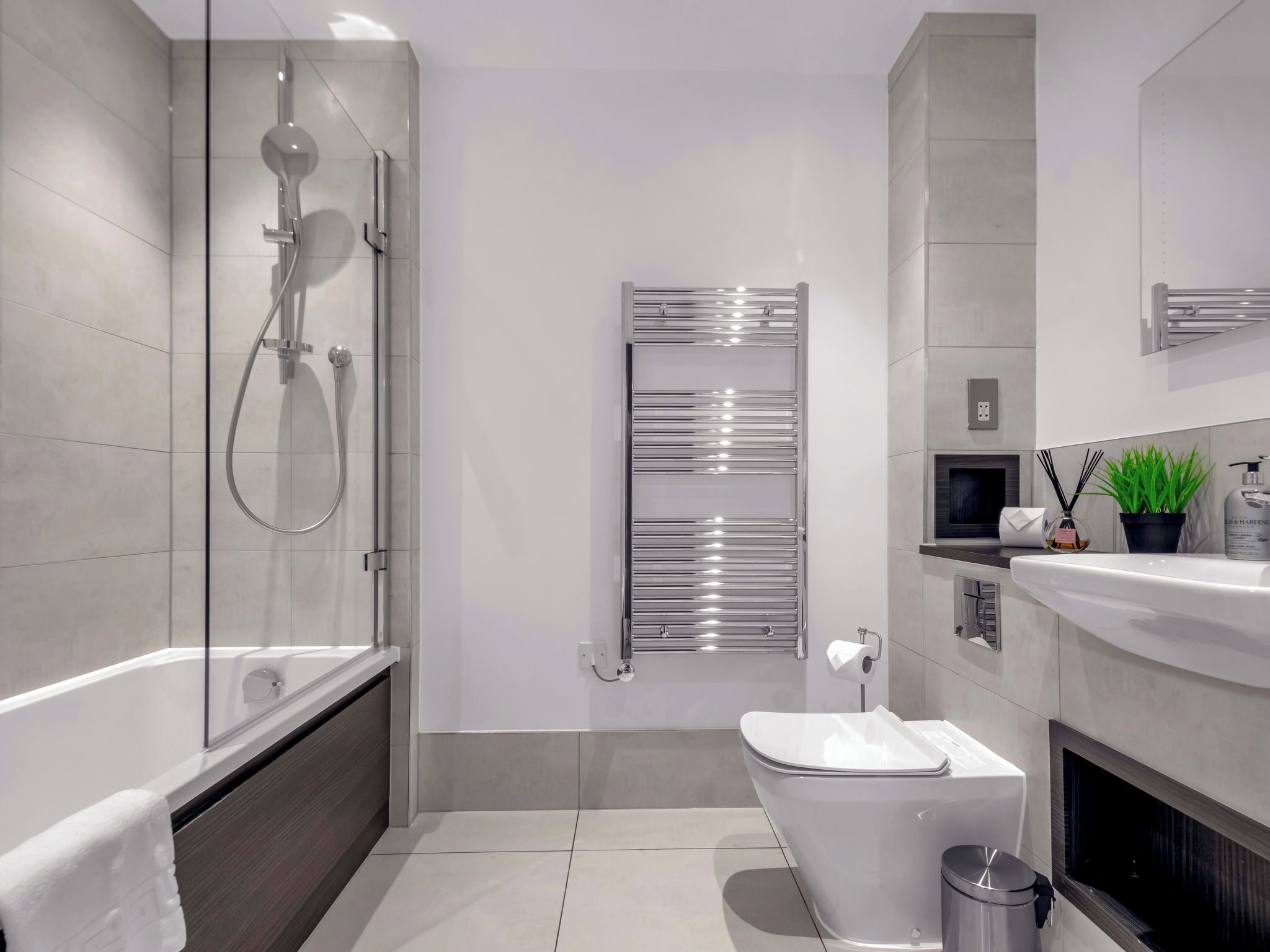 A modern bathroom with a glass-enclosed shower, a white toilet, a built-in sink, and a mirror above the sink.