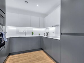 Eine moderne Küche mit grauen Schränken, einer Edelstahl-Spüle und einem eingebauten Backofen.
