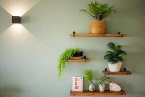 Een muur met drie houten planken waarop planten en een bord staan.