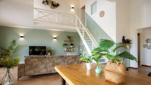 Una sala de estar con un sofá, una mesa de madera y plantas en macetas.