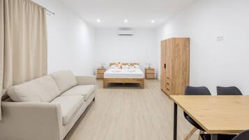 A modern bedroom with a bed, a sofa, a wooden wardrobe, a desk, and a chair.