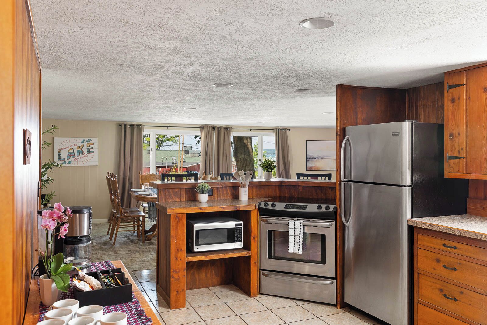 Una cocina compacta con refrigerador, horno, microondas e isla de madera con asientos.